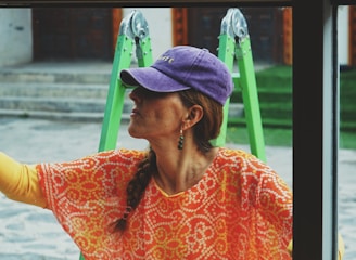 a woman looking out a window with a purple hat on