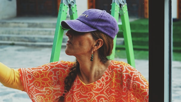 a woman looking out a window with a purple hat on